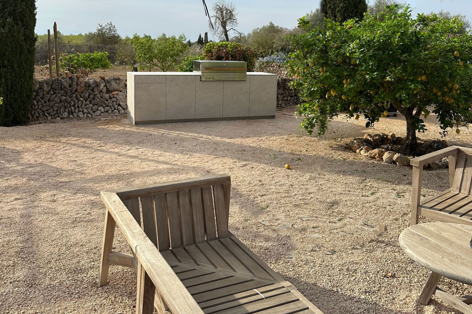 Outdoorküche in heller Keramik mit Flammkraft Grill in mediterranem Garten mit großen Zitronenbaum